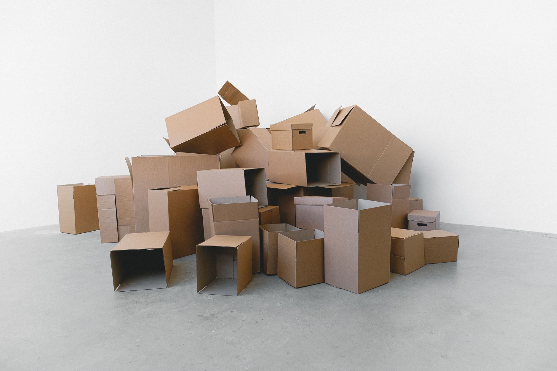 Pile of cardboard containers prepared for relocation on floor at home in daylight on white background